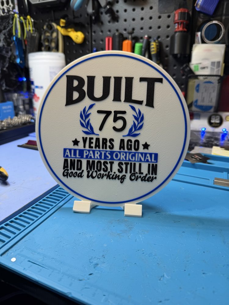 Round 3D-printed sign reading built 75 years ago, all parts original